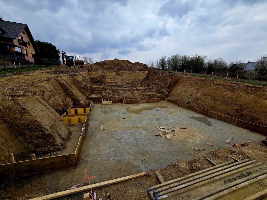 Budowa domu jednorodzinnego Trojanowice - wykop pod fundament z szalunkami i koparka