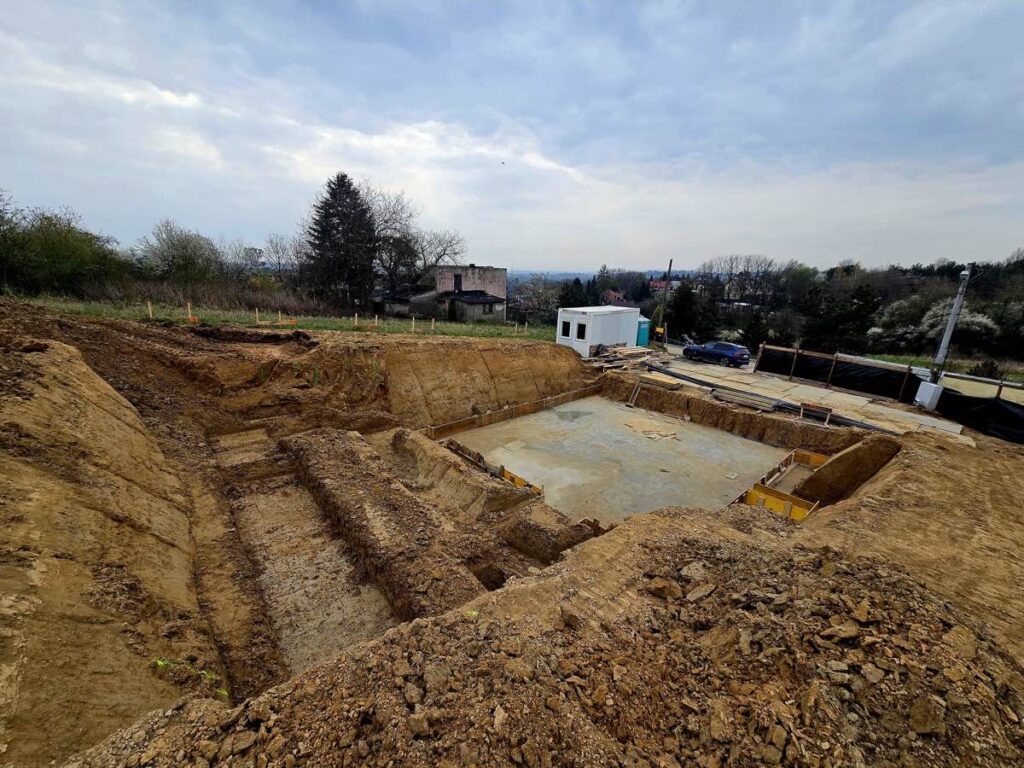 Budowa domu jednorodzinnego Trojanowice - widok wykopu fundamentowego z kontenerem socjalnym