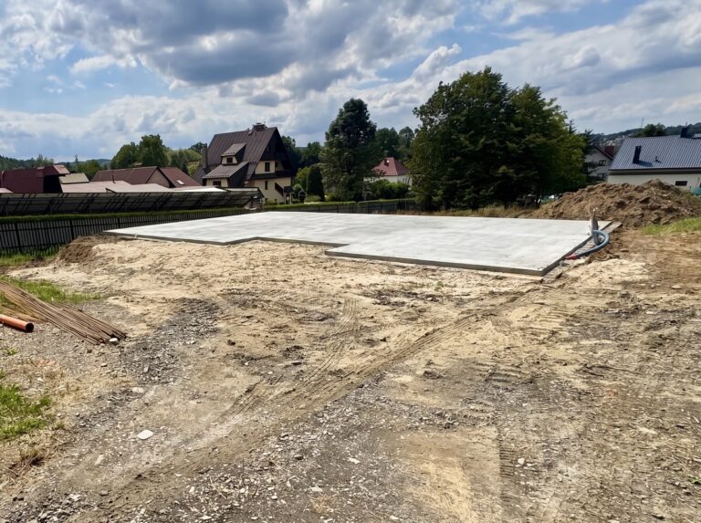 Budowa domu jednorodzinnego Radziszów - płyta z chudego betonu pod dom, widok z poziomu działki